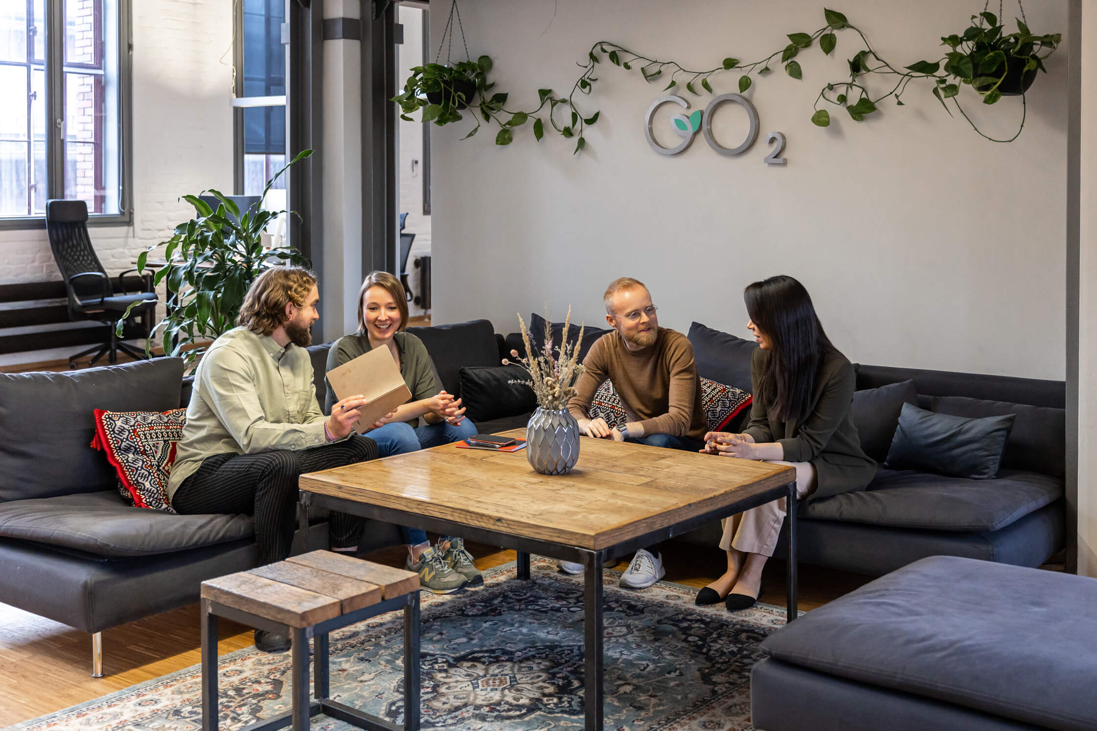 Four people sitting on a couch and talking with each other in an office